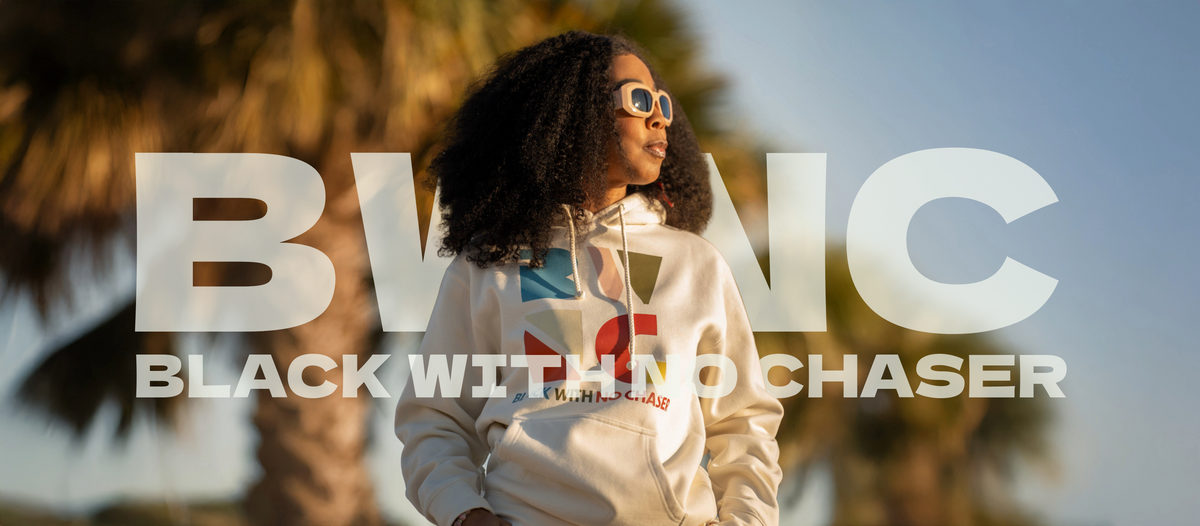 Person wearing a hoodie with 'Black With No Chaser' text against a blurred outdoor background